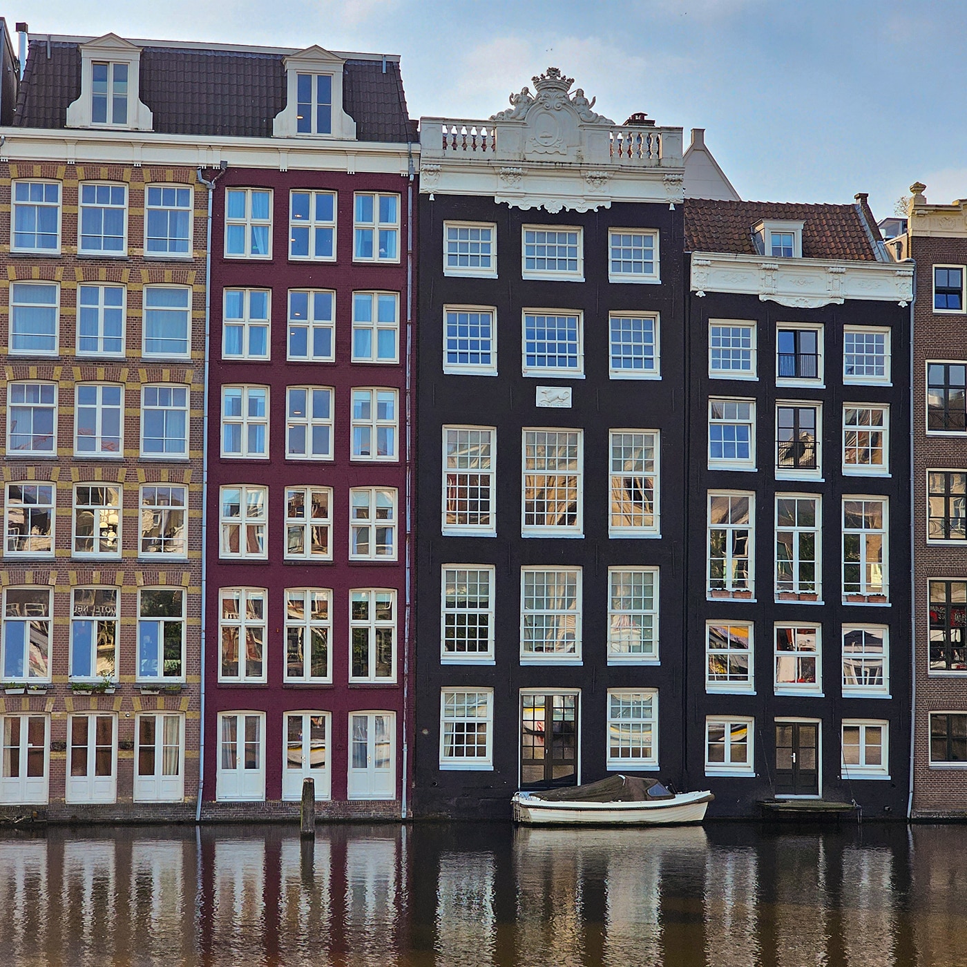 Traditional narrow canal houses in Amsterdam reflected in the water.