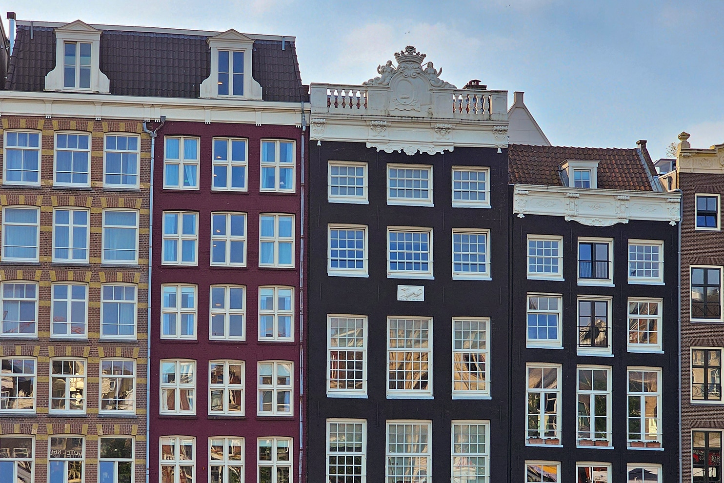 Traditional narrow canal houses in Amsterdam reflected in the water.