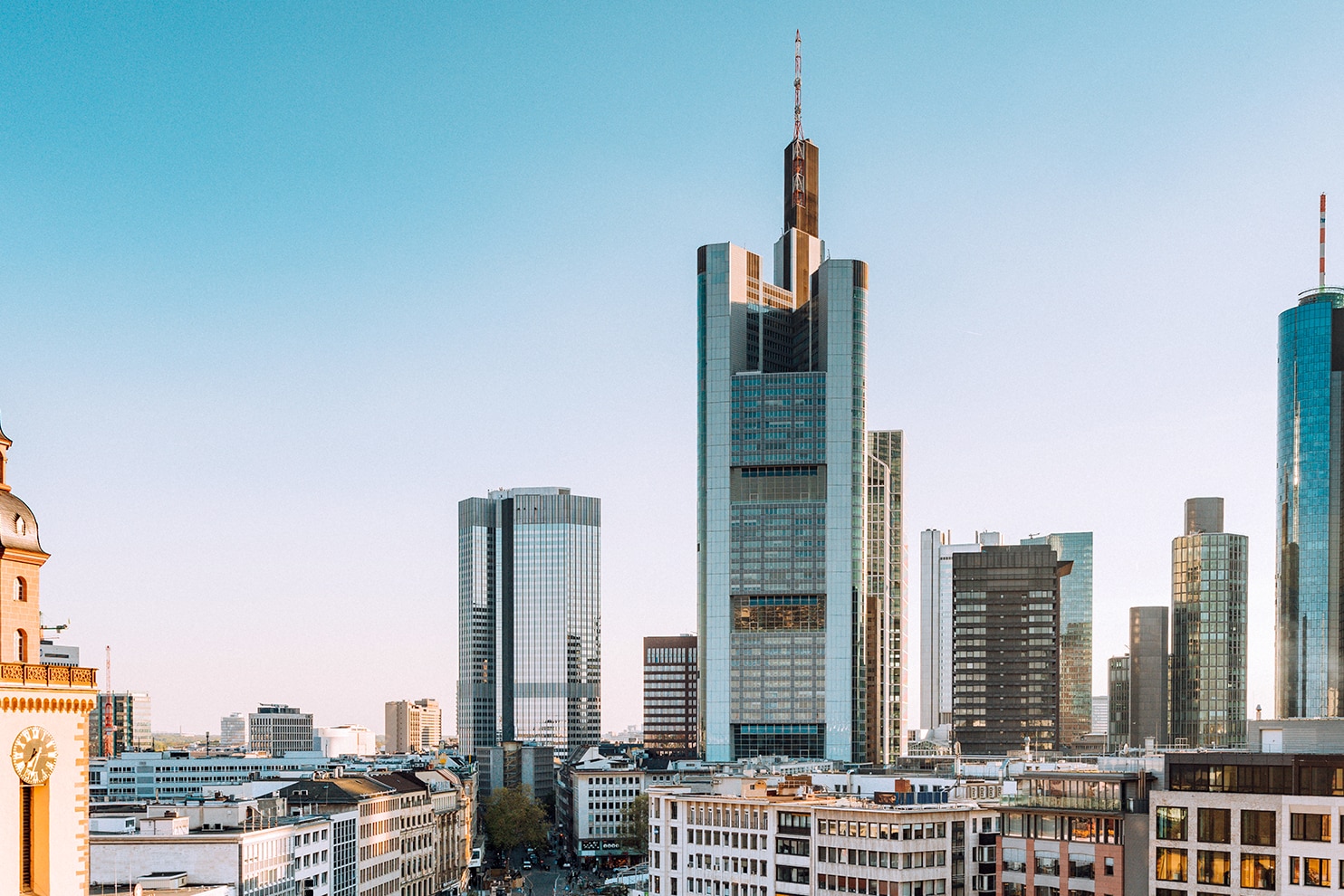 Mix of historic and modern architecture in Frankfurt with skyscrapers and a church tower.