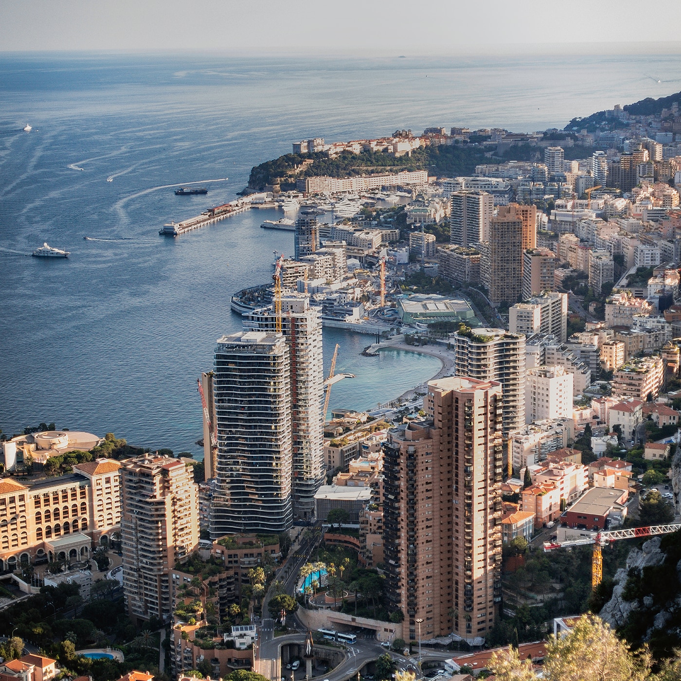 Aerial view of Monaco’s coastal skyline with high-rise buildings and a busy harbor on the Mediterranean.