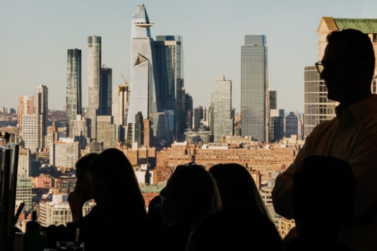 Two business professionals in a conference room having a serious discussion, with a city and water view in the background.