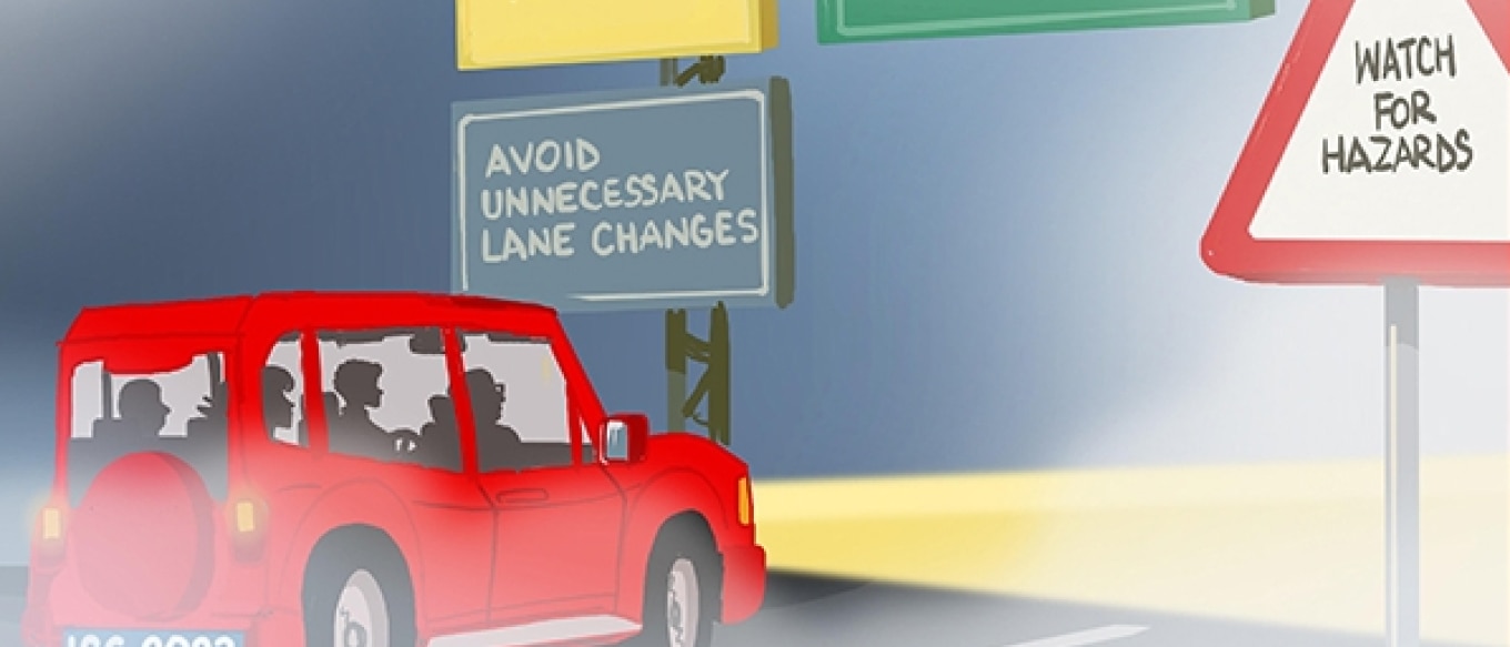 A digital illustration of a red SUV driving through foggy conditions at night. The headlights are on, illuminating the road ahead. The vehicle has passengers inside, and its license plate reads "ISG 2023." Overhead road signs provide safety tips for driving in fog, including "Use Fog Lights," "Avoid Unnecessary Lane Changes," and "Allow Extra Time to Reach Your Destination." A triangular warning sign on the right side of the road reads "Watch for Hazards."