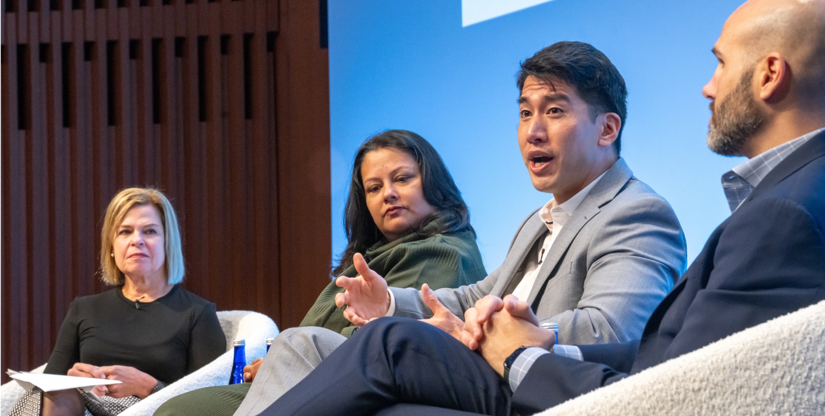 A close up of a panel discussion with two women and two men. One man speaks while the others listen attentively.