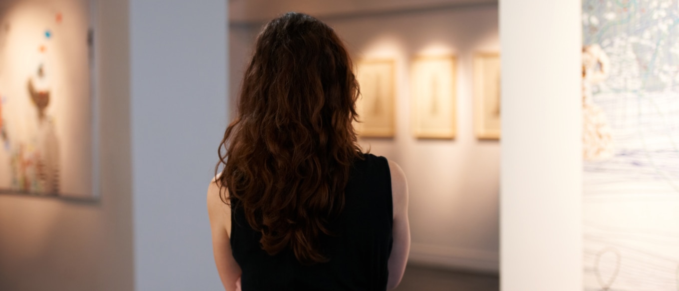 Affluent woman admiring placement of the collectible artwork she once owned.