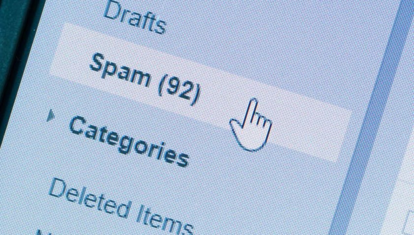 A close-up of a computer screen displaying an email inbox with the spam folder highlighted. The spam folder contains 92 unread messages, and a cursor in the shape of a hand is hovering over it. The image shows pixelation, indicating a zoomed-in digital display