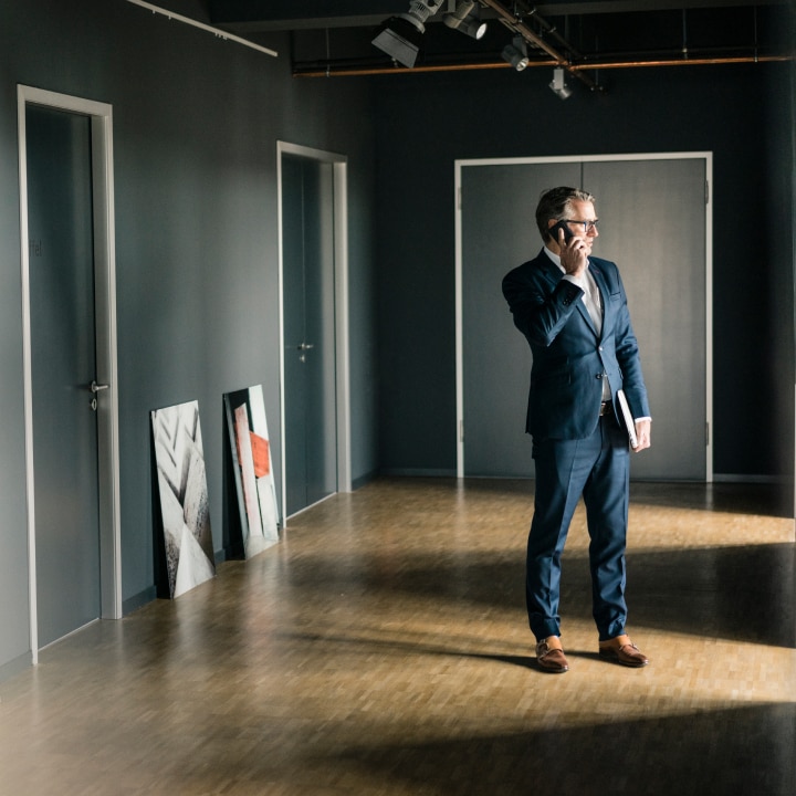 Negotiating the acquisition of art by phone with collectible artwork on floor.