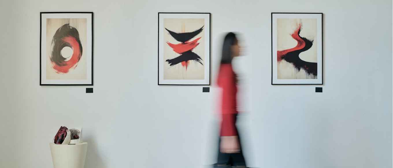 A woman walks across in an art gallery, and additional paintings in the background.