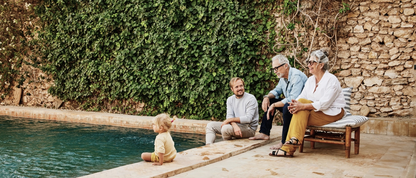 Family including a toddler, a father, a grandmother, and a grandfather relaxing by the pool