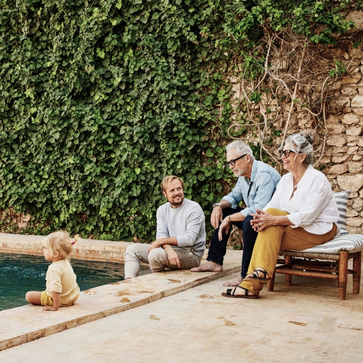 Family including a toddler, a father, a grandmother, and a grandfather relaxing by the pool