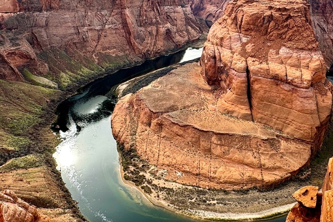 Silhouetted office workers are seen in front of multiple computer monitors with a panoramic view of a city skyline, including modern skyscrapers and a river, visible through large windows